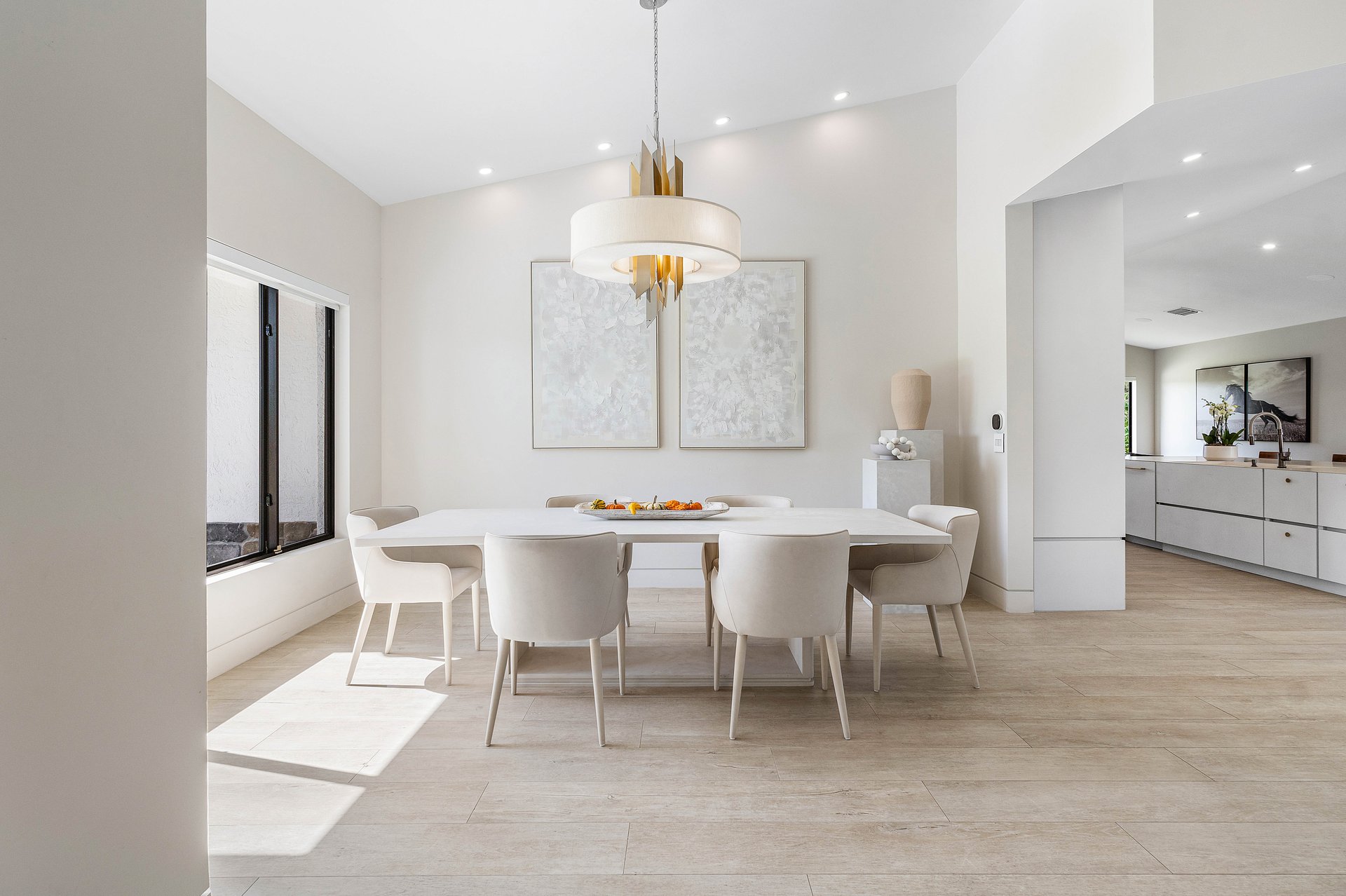 Open dining and kitchen flow with vaulted ceiling and pendant chandelier