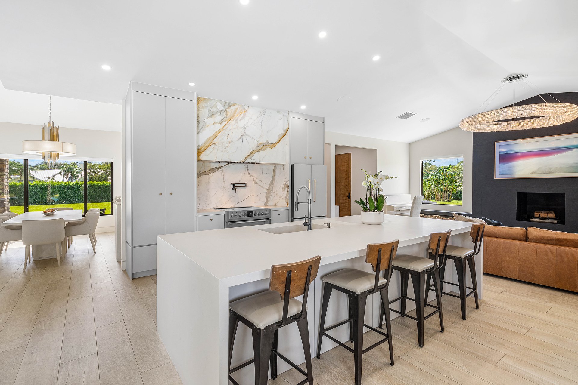Chef's kitchen with quartz waterfall island, marble backsplash, and bar seating