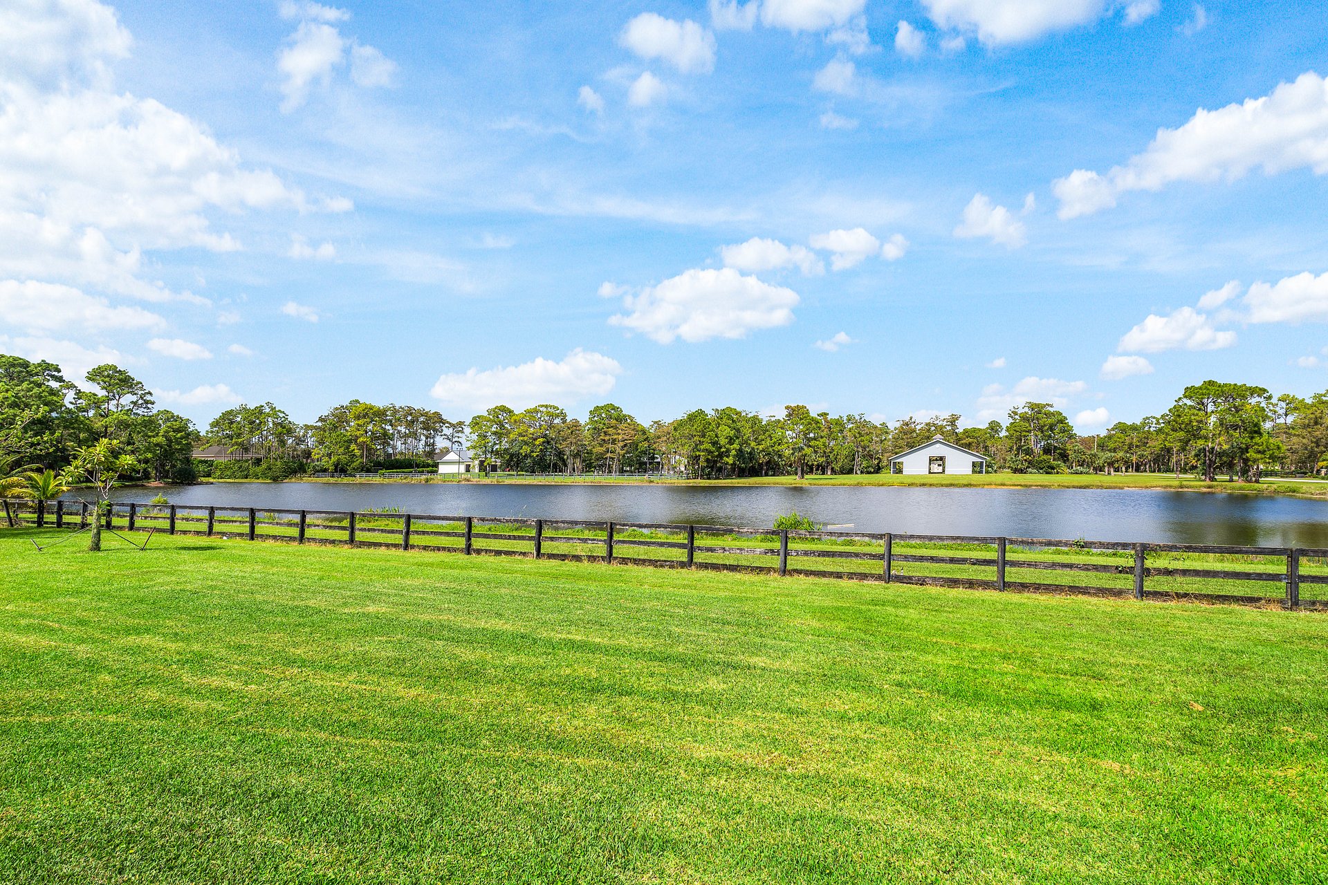 Lakefront view across manicured lawn and post-and-rail fence